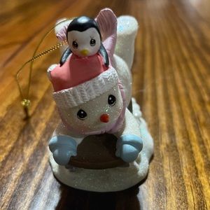 Vintage child snowman sledding snowman with baby penguin ornament.